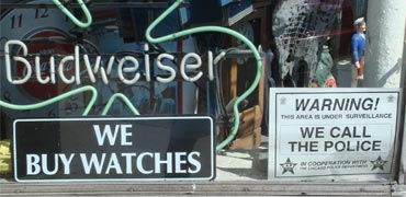 Signs reading 'We buy watches' and 'we can police'