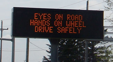 Road sign reading 'Eyes on Road, Hands on Wheel, Drive Safely