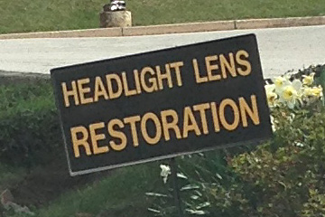 A close-up of a sign reading headlight lens restoration