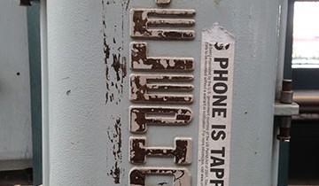 Phone is tapped sticker on a public phone