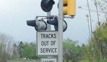 Two signs on a railing crossing: tracks out of service and exempt