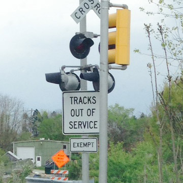 Two signs on a railing crossing: tracks out of service and exempt
