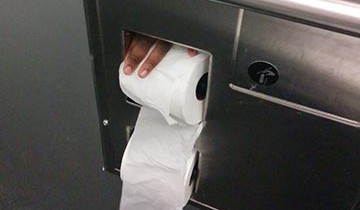 A hand installing a fresh toilet roll