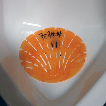A urinal mat with the date 7-24-14 written on it