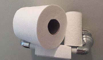 Three toilet paper rolls stacked on a toilet roll dispenser