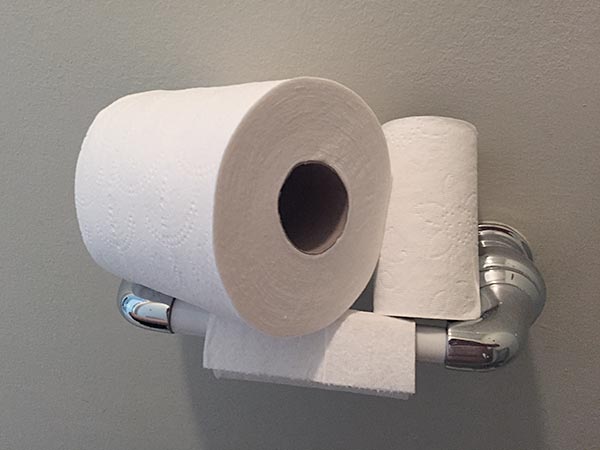 Three toilet paper rolls stacked on a toilet roll dispenser
